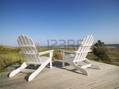 Two Adirondack Chairs On Wooden Deck Overlooking Beach At Bald Head