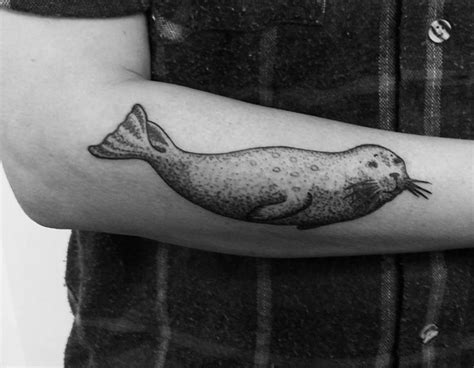 A Black And White Photo Of A Seal On Someones Arm With A Tattoo
