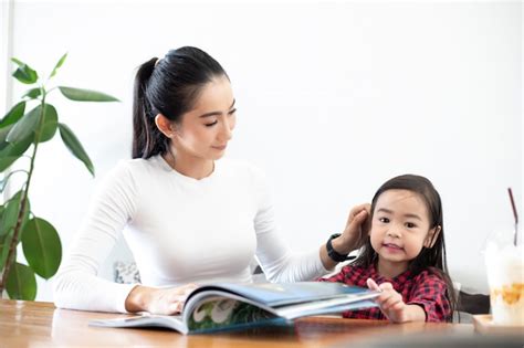 Una Madre Asiática Está Enseñando A Su Hija A Leer Un Libro Durante El