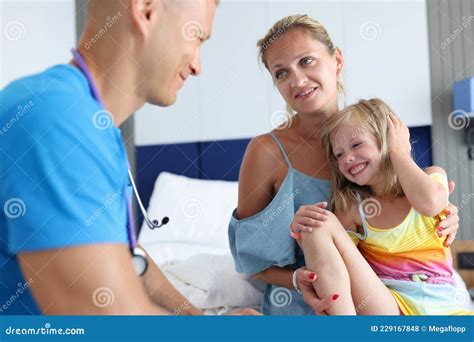 Male Pediatrician Doctor Communicates With Little Girl And Mother At
