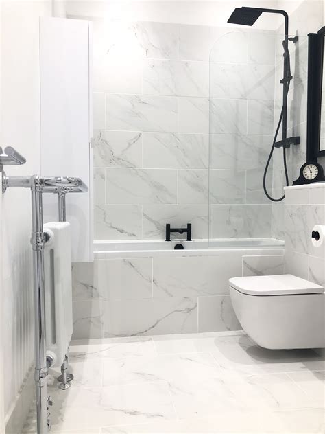 White Marble Tiled Bathroom With Black Shower Taps And Accessories