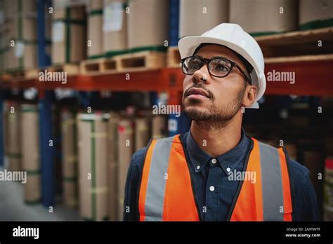 Warehouse Male Supervisor In Uniform And Helmet Thinking Standing In