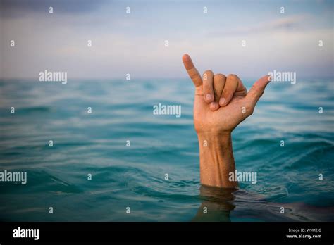 Hand Of Surfer Making Shaka Hang Loose Sign In Tropical Blue Waters