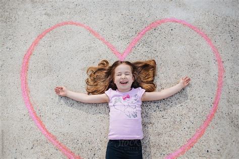 Cute Young Girl Laughing While Laying Inside Of A Heart By Stocksy