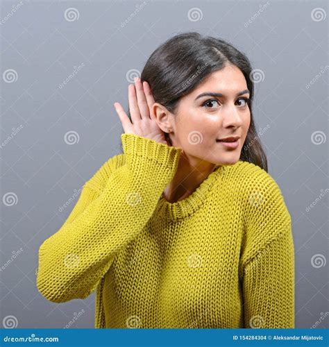 Woman Listening With Hand To Ear Concept Against Gray Background Stock