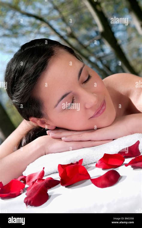 Woman Lying On A Massage Table With Rose Petals In Front Of Her Stock