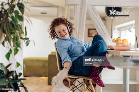 Young Woman Cuddling Her Dog While Working From Home High Res Stock