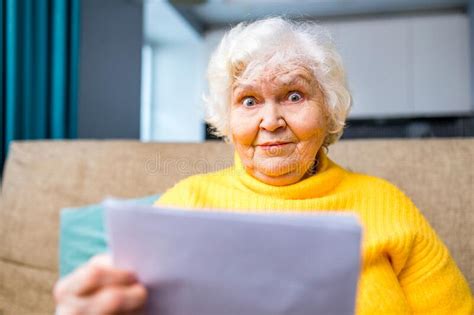 Shoked Amazed Old Woman White Gray Haired Sitting On The Sofa In Living