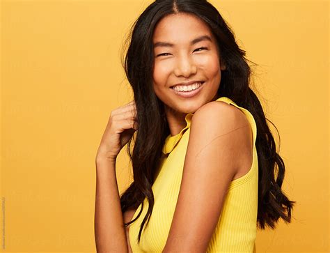 Asian Woman Fun Portrait Smiling Isolated Over Yellow Studio Background By Stocksy Contributor