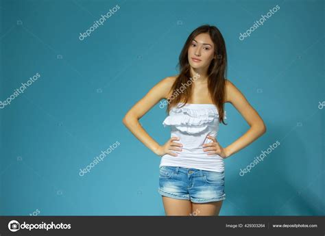 Beautiful Cheerful Teen Girl Jean Shorts White Top Blue Background