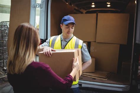 Delivery Driver Handing Parcel To Customer Outside Van Stock Image