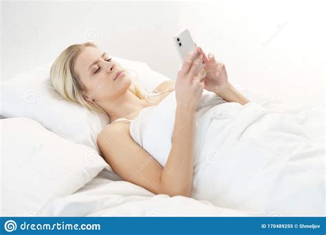 Young Woman Lying In The Bed With A Smartphone Beautiful Blond