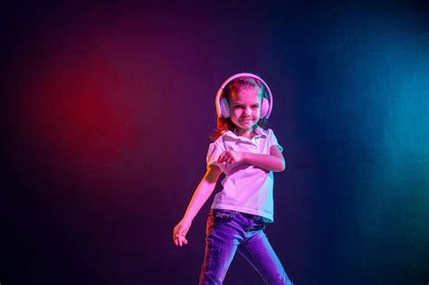 premium photo girl listening to music in headphones on dark colorful wall neon light dancing