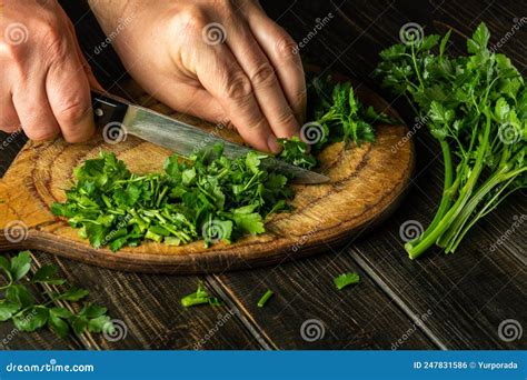 Cook Cutting Green Parsley On A Cutting Board With A Knife For