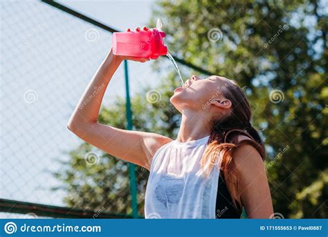 Sporty Young Blonde Woman With Sporty Bottle With Cool Water Pours Water On Herself On Sports ...
