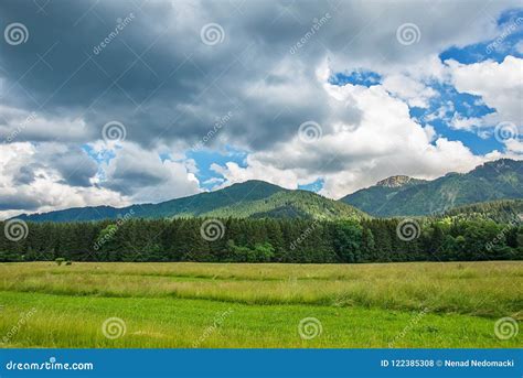 Idyllic Landscape In The Alps With Green Meadows And Clouds Stock