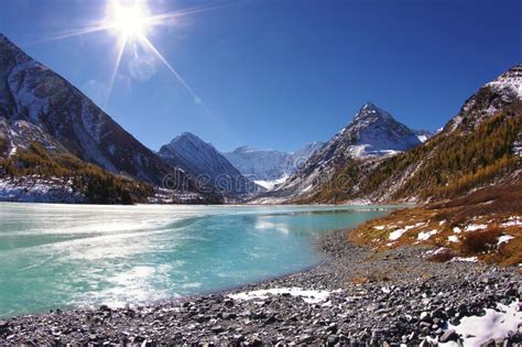 Turquoise Mountain Lake Under The Ice With Blue Sky And Sun Stock Photo