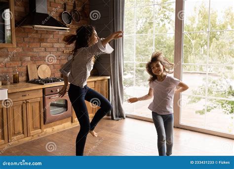Excited Mom And Daughter Girl Dancing To Music In Kitchen Stock Image