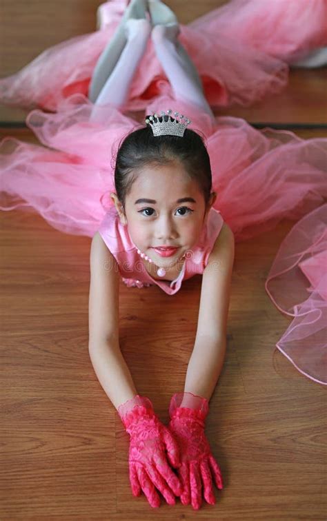 adorable little ballerina girl in a pink tutu lying on the floor with looking at camera stock