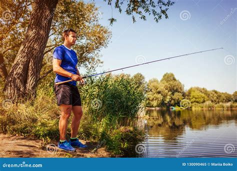 Young Man Fishing On River Bank Fisherman Enjoying Hobby Stock Image
