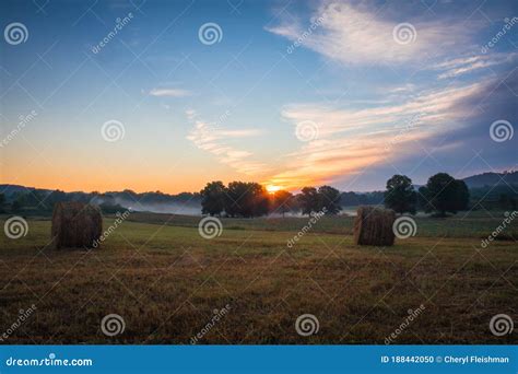 Hay Bales Rolled On Field At Sunrise With Fog Creates Amazing Sky In