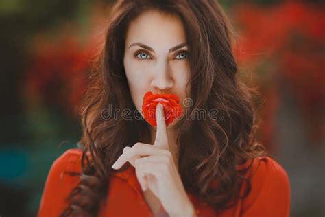 Close Up Portrait Of Beautiful Brunette Woman With Red Rose In Her Lips