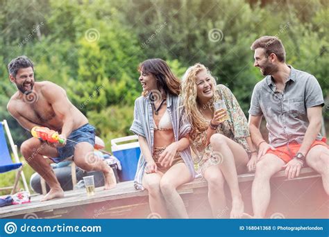 Cheerful Shirtless Man Spraying Water With Squirt Gun On Friends