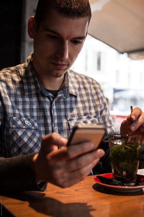 Man Checking Smartphone In A Cafe By Stocksy Contributor Mosuno