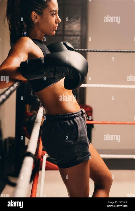Confident Female Boxer Leaning Against The Ropes In A Boxing Ring