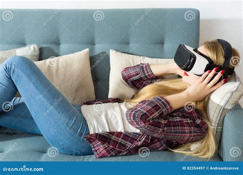 Attractive Woman Wearing Virtual Reality Glasses Lying On A Couch