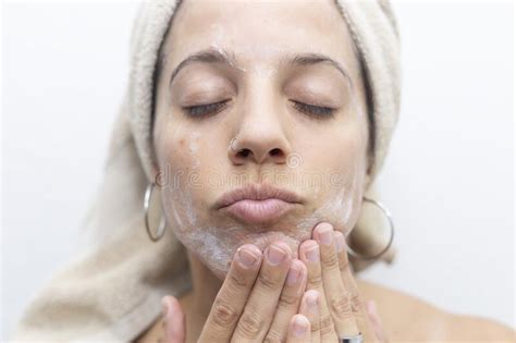 Latina Woman Rubbing Skin Care Cream On Her Face She Has A Towel On