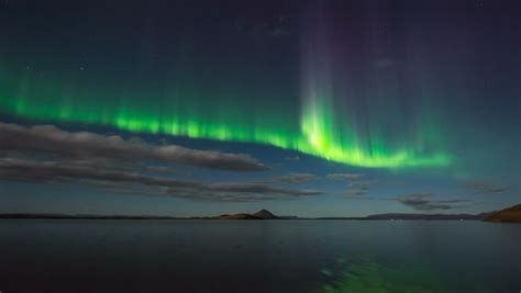 Bright Glowing Aurora Borealis Reflecting Over Calm Ocean Iceland 4k