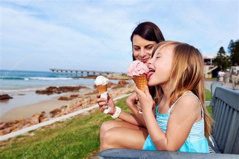 Mamá y su hija disfrutan del helado en la playa