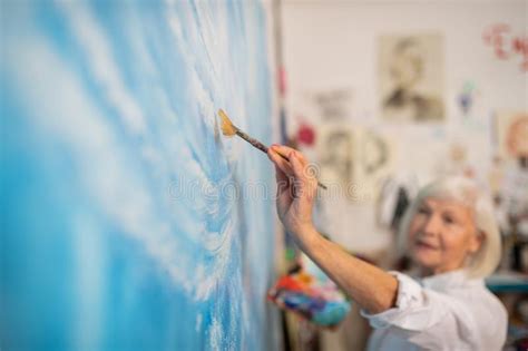 Aged Artist Holding Painting Brush And Coloring Canvas Stock Image