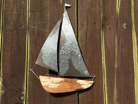 This hand painted wood ships wheel wall hanging decor is the perfect addition to any nautical setting. tin and wooden sail boat wall art