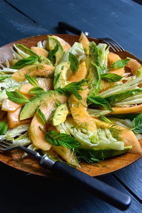 A Wooden Plate Topped With Lettuce And Orange Slices