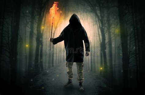Man Coming From Dark Forest With Burning Flambeau In His Hand Concept