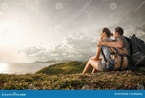 Couple Tourists With Backpacks Enjoying Sunset On Top Of A Mount Stock