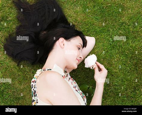 Woman Laying On Grass Smelling Rose Stock Photo Alamy