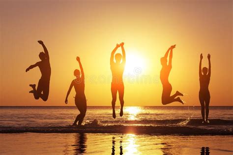 Group Of Happy People Jumping In The Sea At Sunset Stock Photo Image