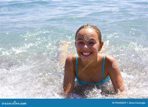 Young Pretty Smiling Girl In Blue Swimsuit In The Sea On The Beach