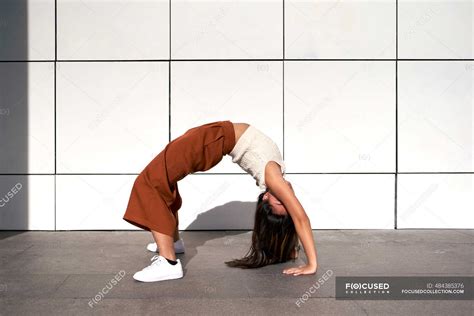 Young Woman Bending Over Backwards Against Wall During Sunny Day — Hair