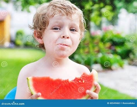 Caucasian Little Boy With Blond Hairs Eating Fresh Watermelon In Stock