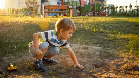 3 Years Old Little Boy In T Shirt And Shorts Sitting On The Ground At