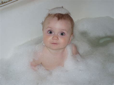 Gather the supplies you'd use for a sponge bath, a cup of rinsing water and baby shampoo, if needed, ahead of time. Baby Playing In Bath Tub