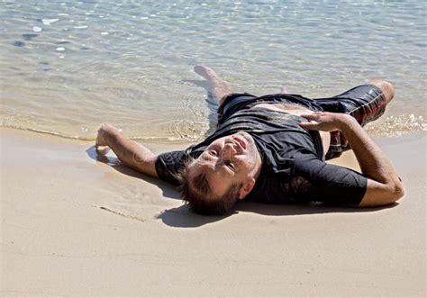 Homem Esgotado Que Encontra Se Na Praia Foto De Stock Imagem De Sair