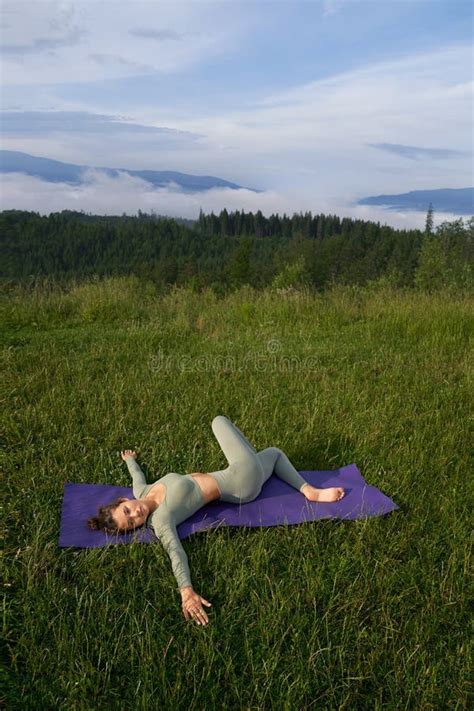 Woman Lying On Yoga Mat And Stretching Legs Outdoors Stock Image