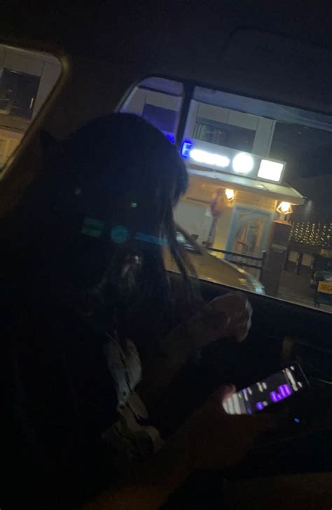 A Woman Sitting In The Passenger Seat Of A Car At Night Using Her Cell