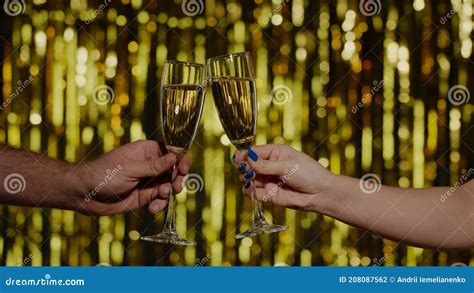 Two Hands With Glasses Of Champagne Wine Or Cocktail Making Cheers Raising Toast On Gold