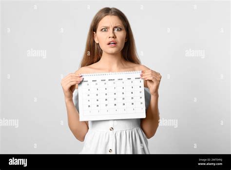 Emotional Young Woman Holding Calendar With Marked Menstrual Cycle Days